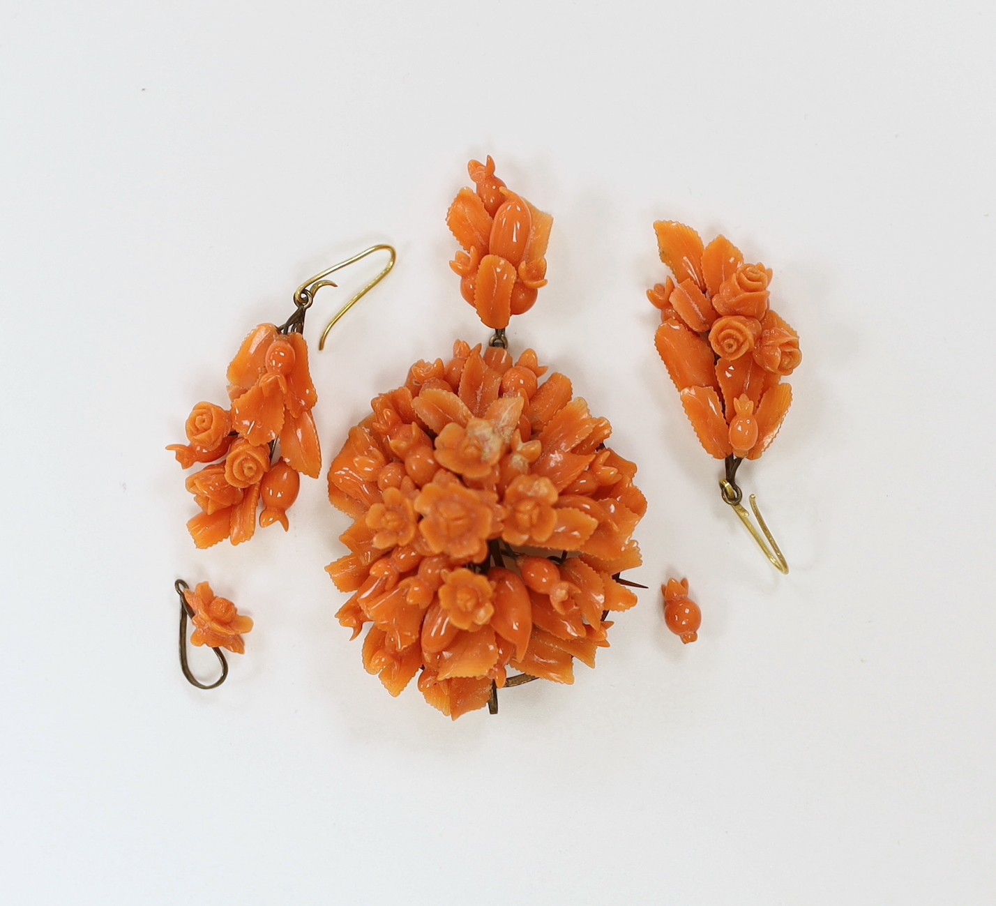 A late 19th/early 20th century gilt metal mounted drop pendant coral brooch carved as a bouquet of flowers, 68mm and a pair of similar earrings(a.f.)